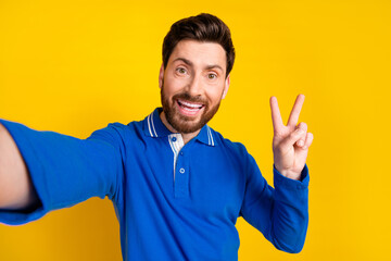 Fototapeta premium Photo portrait of handsome young guy take selfie v-sign dressed stylish blue garment isolated on yellow color background