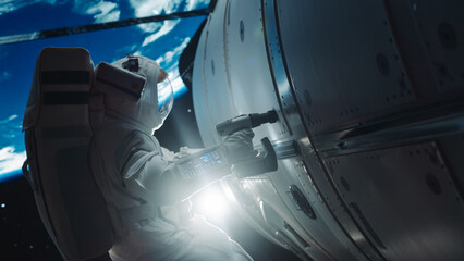 Space Engineer Servicing a Panel on a Communication Satellite with an Automatic Screw Gun. Brave Astronaut Working in Outer Space with Beautiful Blue Planet Earth in the Background