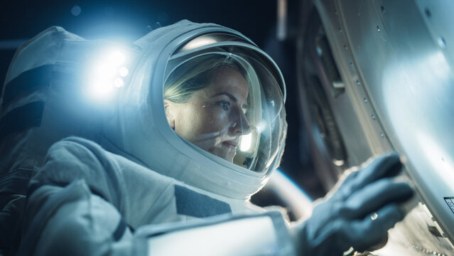 Close Up Portrait of Professioanal Astronaut Performing a Routine Maintenance Check Outside a Spacecraft in Zero Gravity in Outer Space. Technology, Scientific Exploration, Female Empowerment Concept