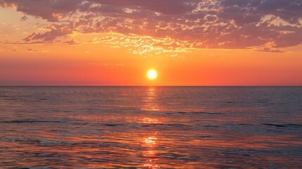 As the sun dips below the horizon, the sea glistens with hues of orange and pink.