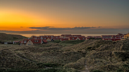 modern houses among the dunes at sunset by the sea