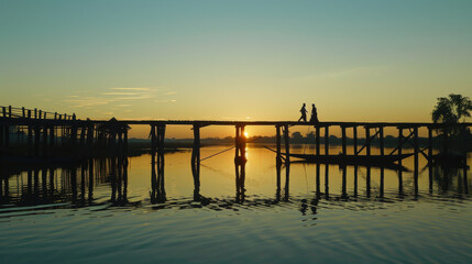 A serene landscape of the U Bein Bridge at sunset, with silhouettes of people walking across the longest teak bridge in the world
