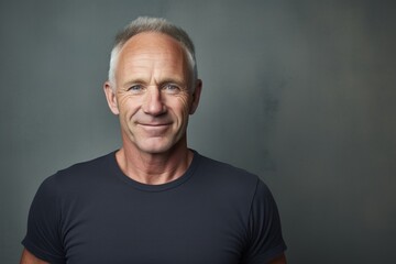 Obraz premium Portrait of a grinning man in his 50s donning a classy polo shirt in front of bare concrete or plaster wall