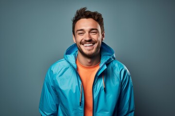 Fototapeta premium Portrait of a happy man in his 30s wearing a functional windbreaker over blank studio backdrop