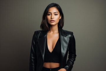 Obraz premium Portrait of a blissful woman in her 20s sporting a stylish leather blazer over blank studio backdrop
