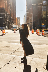 A young woman dances in the streets of New York City, bathed in warm sunlight.