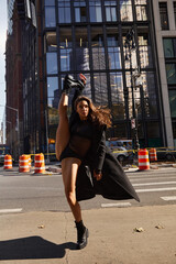 A young woman dances on a city street in New York City.