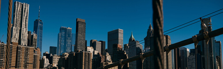 Fototapeta premium A view of the Manhattan skyline, captured through the cables of a bridge.