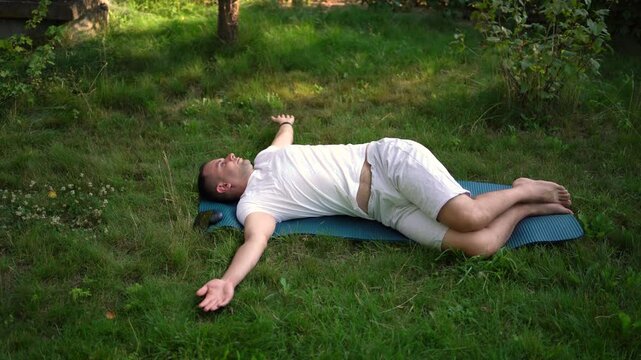  man performs somatic exercises in the garden in the morning