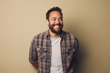 Obraz premium Portrait of a cheerful man in his 40s wearing a comfy flannel shirt while standing against light wood minimalistic setup