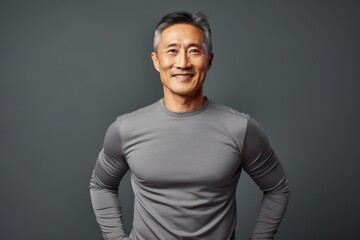 Obraz premium Portrait of a tender asian man in his 50s sporting a technical climbing shirt isolated in light wood minimalistic setup