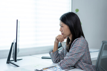 A woman is sitting at a desk with a computer monitor in front of her
