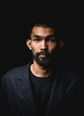 Obraz premium Portrait of young man with a beard and mustache and looking at camera in black studio on background.