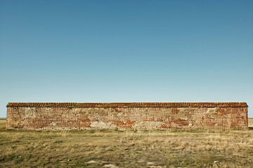 Imposing Brick Wall Under a Clear Blue Sky: A Symbol of Resilience and Division