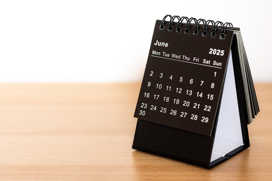 June 2025 black calendar - month page on the wooden desk