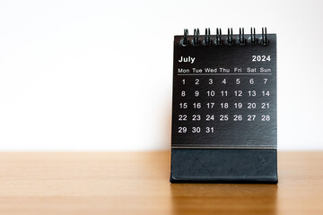 July 2024 black calendar - month page on the wooden desk