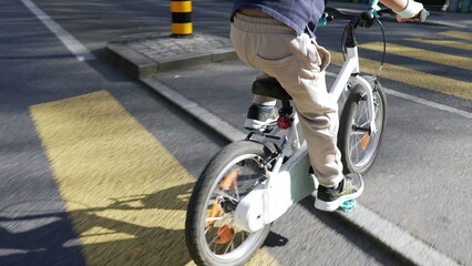 Boy on bicycle wearing protective helmet cycling on city street with crosswalk and vehicles, emphasizing safe cycling practices and active childhood in urban settings, perfect for health 