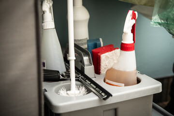 A storage caddy is filled with essential cleaning supplies including sprays, scrubbers, and tools,...