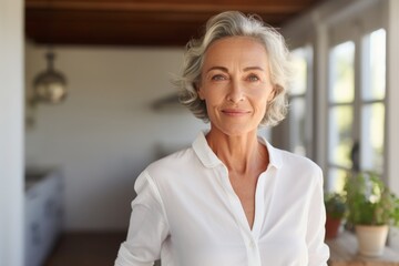 Portrait of a blissful woman in her 60s wearing a simple cotton shirt while standing against stylized simple home office background