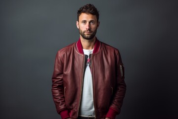 Fototapeta premium Portrait of a tender man in his 30s sporting a stylish varsity jacket in plain cyclorama studio wall