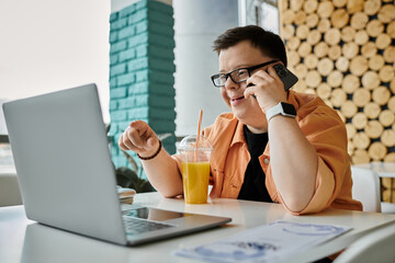 A man with Down syndrome smiles as he works remotely on his laptop and talks on his phone at a cafe.