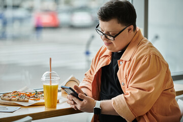 A man in a cafe checks his phone while enjoying a slice of pizza.