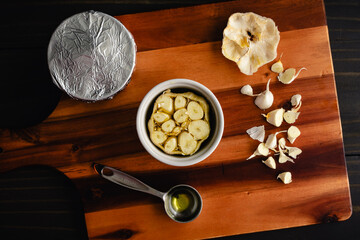 Preparing a Garlic Bulb to be Roasted in a Ramekin: Sliced open head of garlic drizzled in olive oil and placed inside a ceramic dish