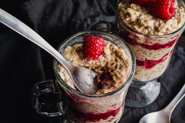 Raspberry Peanut Butter Oat Parfaits with Spoon: Healthy layered breakfast with raspberries, rolled ots, fruit, and chia seeds in Irish coffee glasses