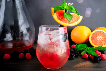 Sake Sangria Garnished with Cara Cara Orange Slice: Fusion cocktail made with sake, oranges, raspberries, and blackberries served over ice cubes