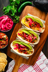 Tex-Mex Migas Breakfast Tacos in a Taco Holder: Overhead view of breakfast tacos with eggs, sliced avocado, pickled onions, and salsa