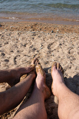 A gay couple is relaxing by the sea, sunbathing on the beach.
