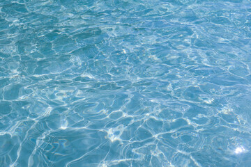 Blue water with ripples on the surface. Defocus blurred transparent blue colored clear calm water surface texture with splashes and bubbles. Water waves with shining pattern texture background.