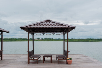 Wooden gazebo on the water of the lake. Holiday, summer weekend.