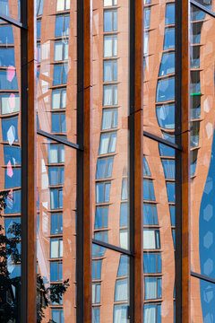 An urban building with highly reflective glass panels displaying an abstract architectural design, symbolizing modern genius and artistic expression in urban city planning.