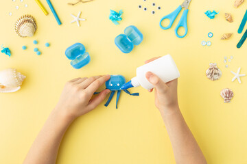 Adorable jellyfish made from plastic blue egg, Kids craft at home or kindergarten. Hands making DIY summer crafting with children. Ocean's day.