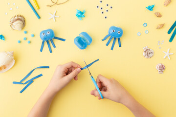 Adorable jellyfish made from plastic blue egg, Kids craft at home or kindergarten. Hands making DIY summer crafting with children. Ocean's day.