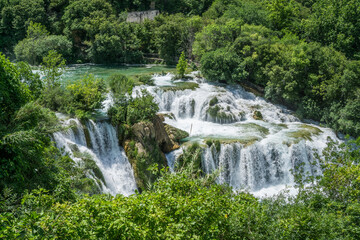 Obraz premium Waterfall among the green summer forest.