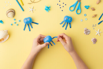Adorable jellyfish made from plastic blue egg, Kids craft at home or kindergarten. Hands making DIY summer crafting with children. Ocean's day. © Angelina Zinovieva