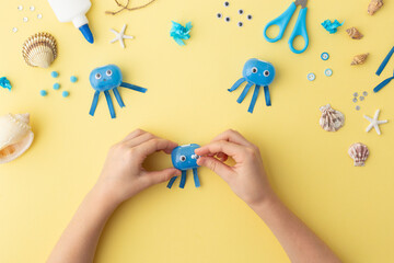 Adorable jellyfish made from plastic blue egg, Kids craft at home or kindergarten. Hands making DIY summer crafting with children. Ocean's day.