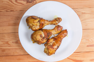 Baked chicken drumsticks on dish on rustic table, top view