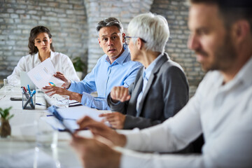 Mid adult  businessman and his female colleague  analyzing chart during a meeting in the office.