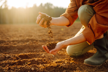 Close-up of a farmer hands holding black soil in their hands, fertile land. Garden field ground fertile concept. - Powered by Adobe