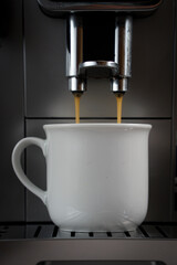 Modern coffee machine with cup and flowing coffee