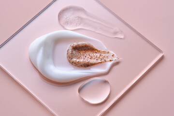 Textures of different cosmetic products on a pink background on a square transparent stand.