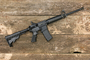 AR15 assault rifle with an adjustable stock on the background of old boards. Right side.