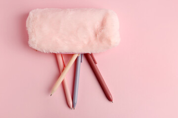 Fallen pencil case with pens on pink background. Top view