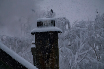 Russian winter in northern olden time hamlet. Snowfall. Smoke is coming from chimney. Frozen...