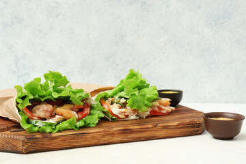 Tasty doner kebabs and sauce on light  background