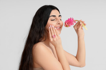 Pretty young woman with hyacinth flower on white background