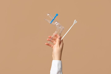 Doctor's hand with pap test tools on beige background